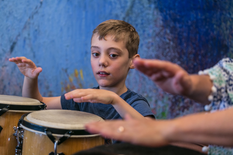 A photo of a young boy playing percussion alongside another person