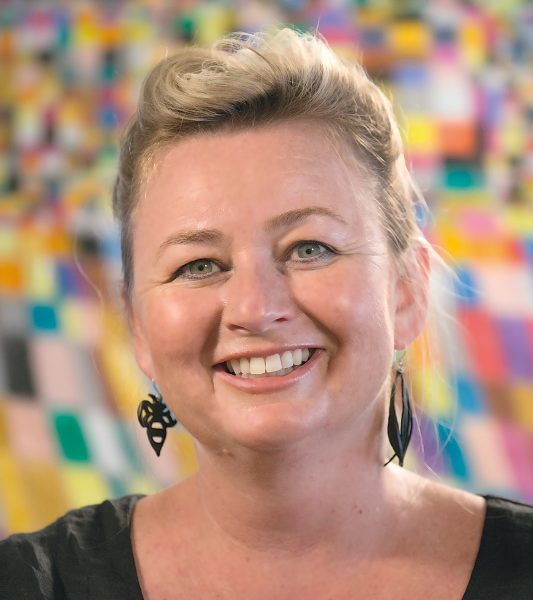 Headshot of Jane Gronow with a colourful artwork as backdrop