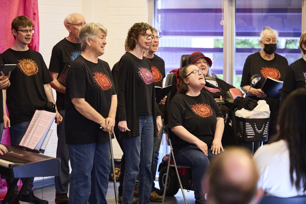 A group of people standing and singing in front of an audience