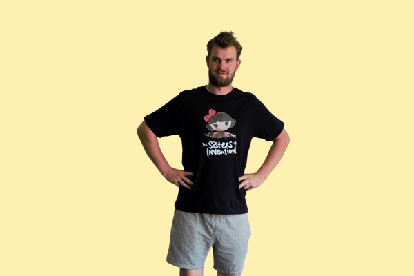 Person wearing black t-shirt with The Sisters of Invention logo featuring a doll's head in black paint.