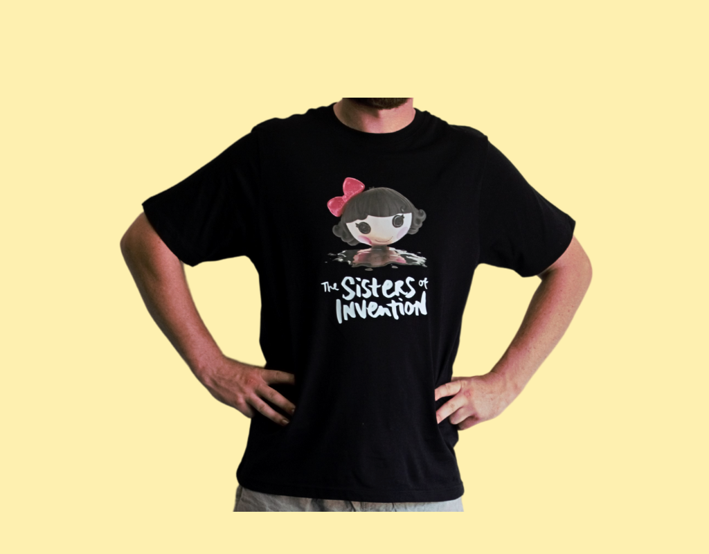 Person wearing black t-shirt with The Sisters of Invention logo featuring a doll's head in black paint.