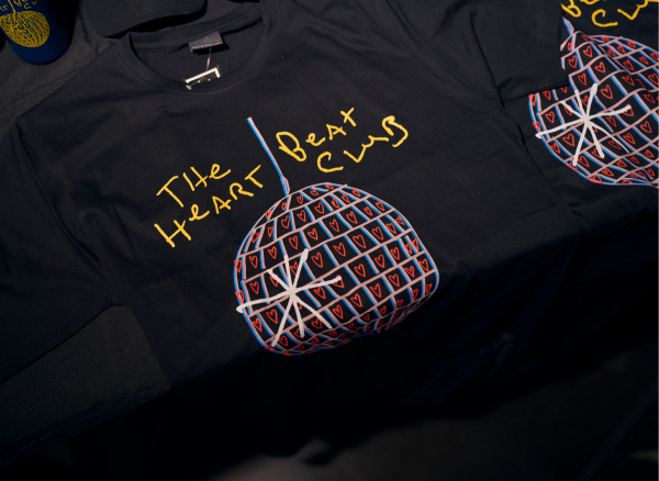 A black cotton t-shirt with large Heart Beat Club logo in colour on the front.