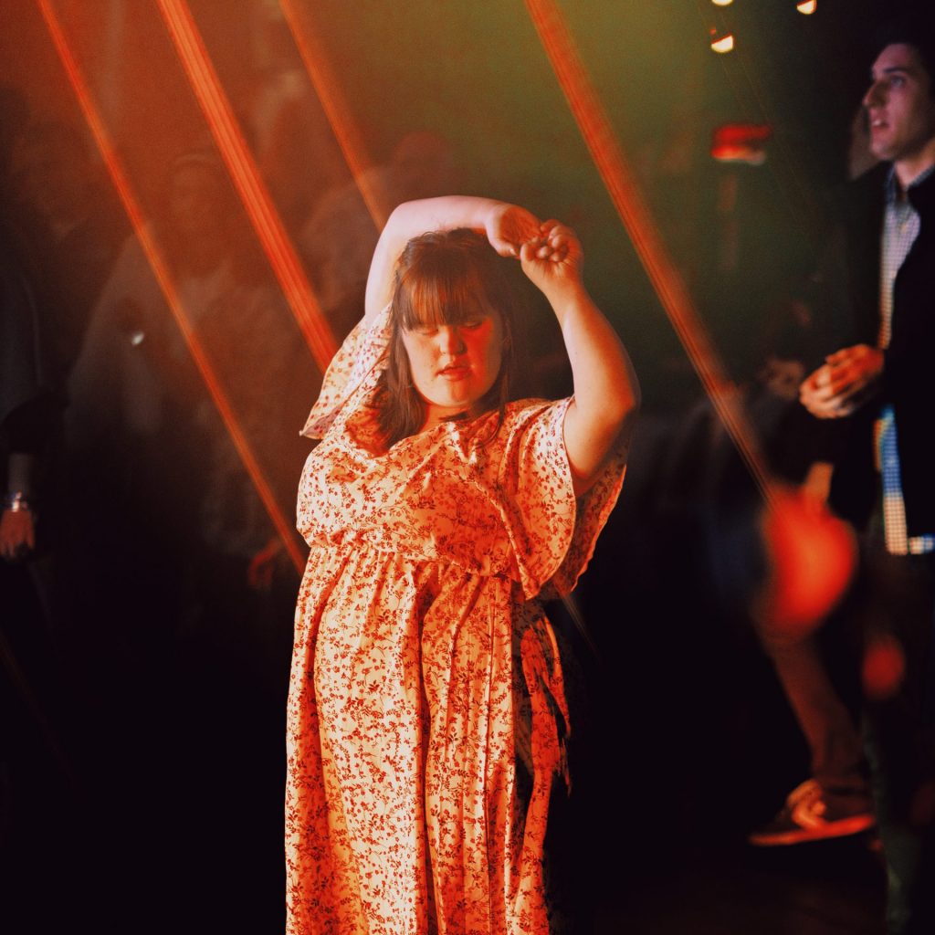 person dancing at the Heart Beat Club with their hands above their head. 