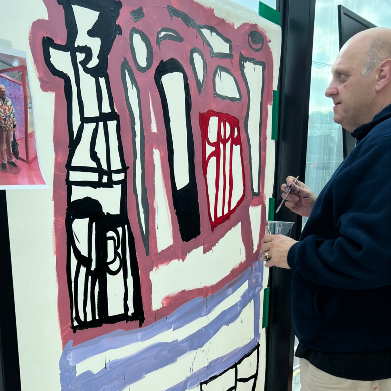 Lewis painting on a canvas taped to a window in Korea.