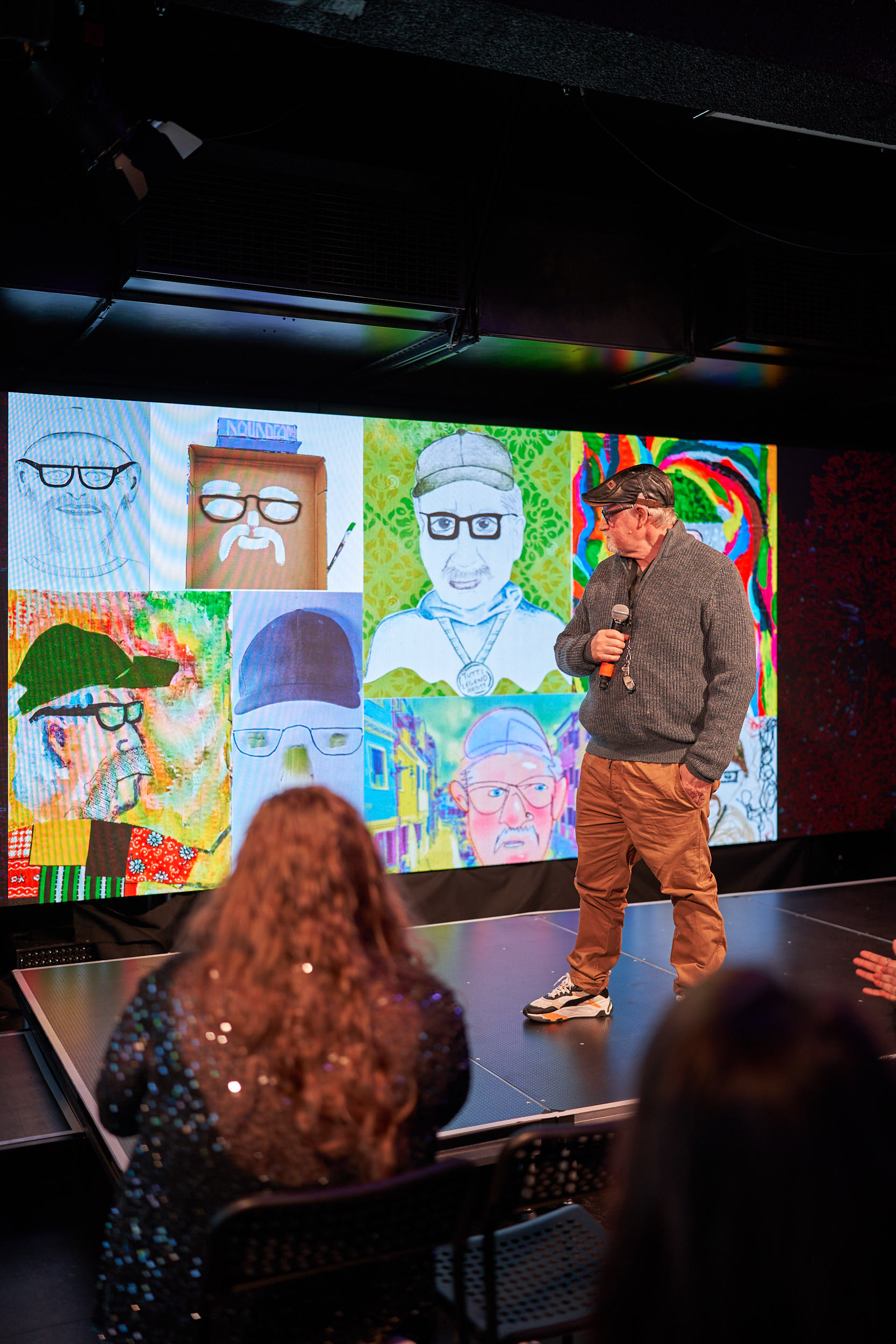 Jeff presenting at SALA slide night 2025 - he's on stage holding a microphone at his presentation slide showing portraits of Jeff from freinds.