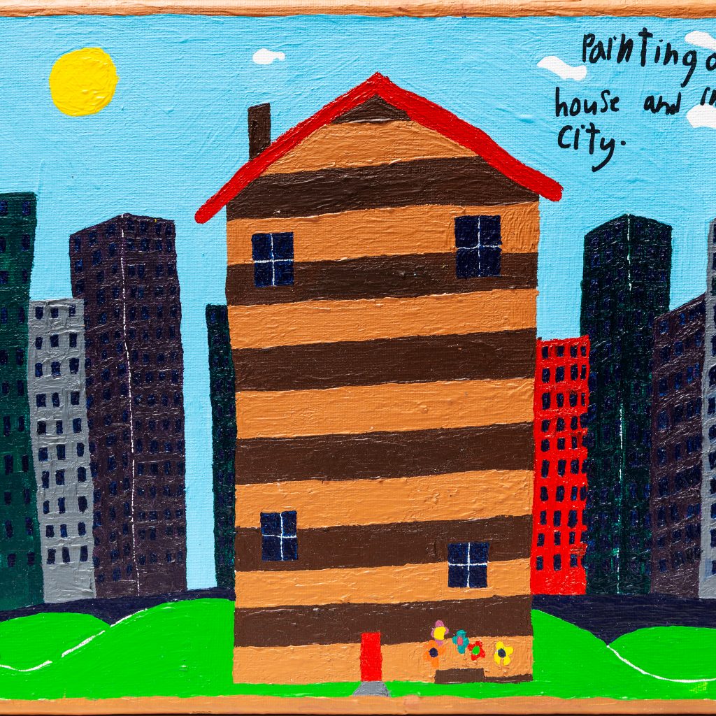 A tall house in the city - it's brown and orange striped with a red roof and four small windows. There is a small flower garden out the front. Behind the house is a city scape, dark, grey and tall contrasted by a bright blue sky and yellow sunshine.