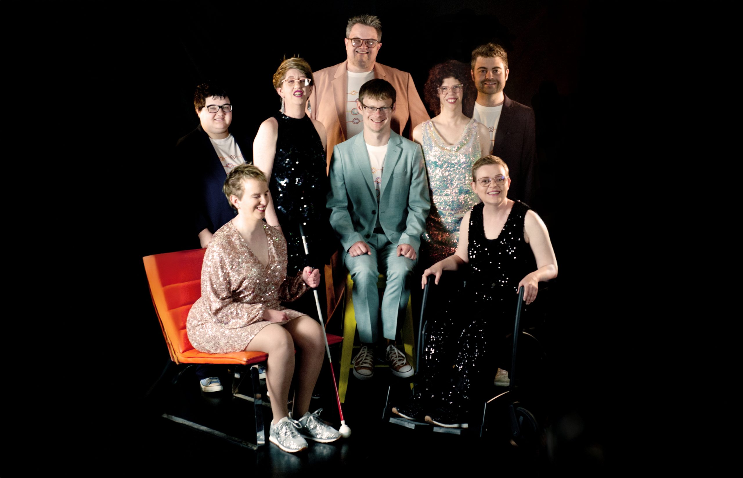 Professional photo shot of TGIF - some members standing and others sitting in a group and all smiling at the camera.