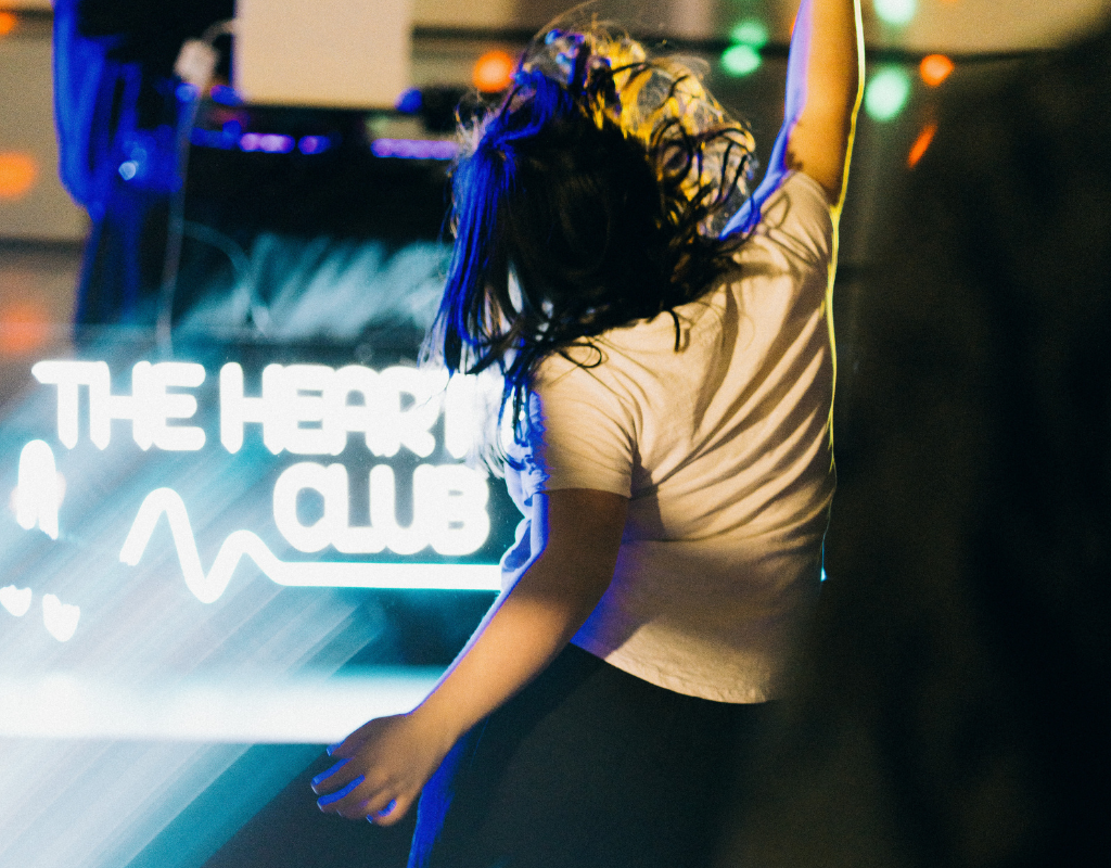 Person dancing with a fist in the air at the Heart Beat Club. 