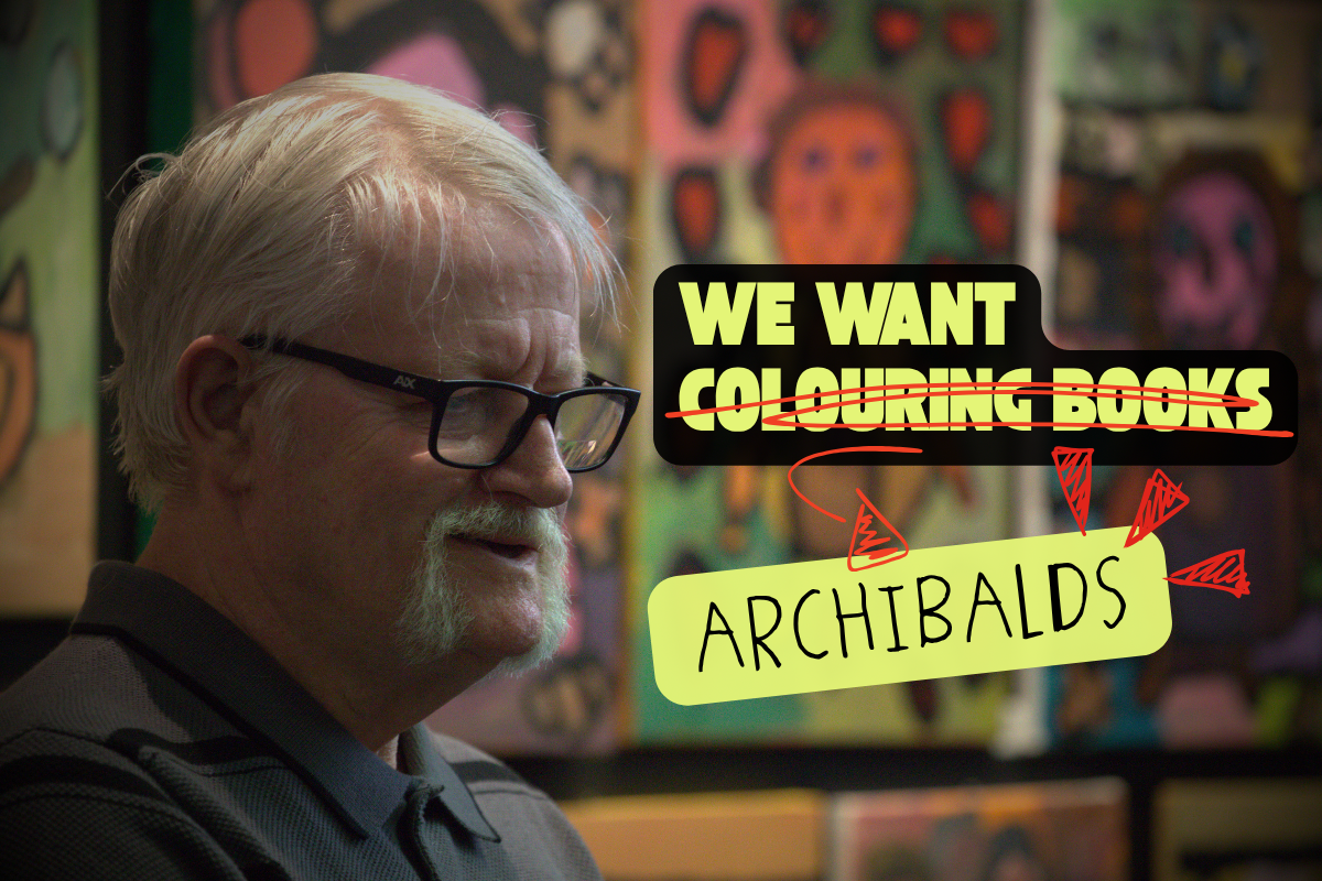 Disabled artist with glasses and moustache, with the text 'We want colouring books [colouring books scored out] Archibalds.'
