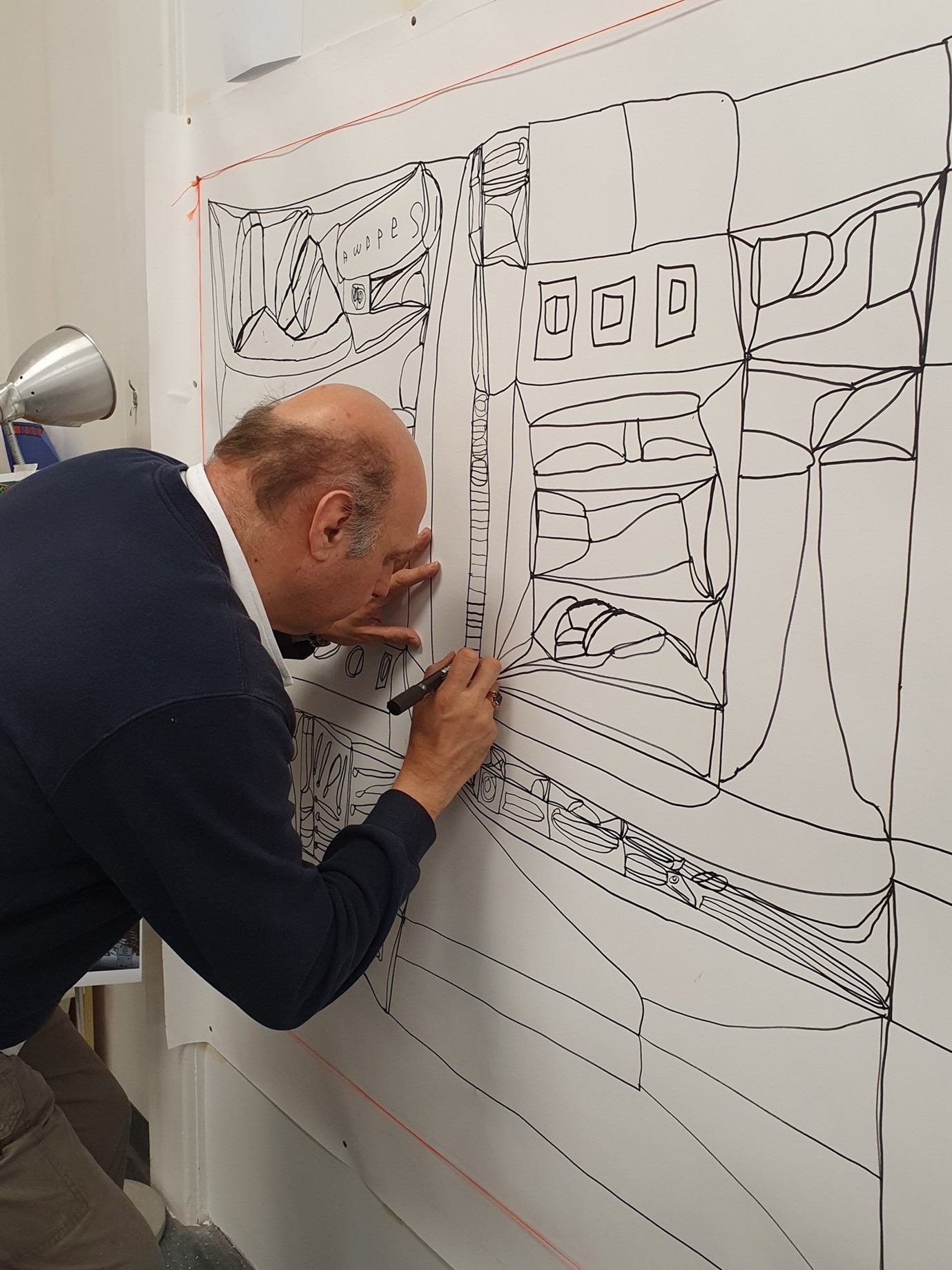 Lewis drawing a large scale work with pen. 