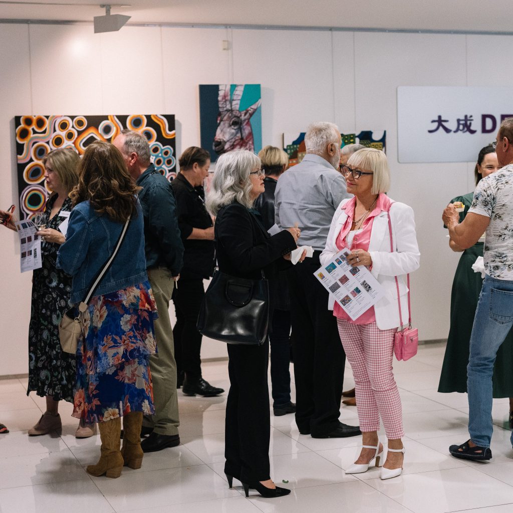 A group of people mingling at Dentons - there are Tutti artworks on the wall behind them.