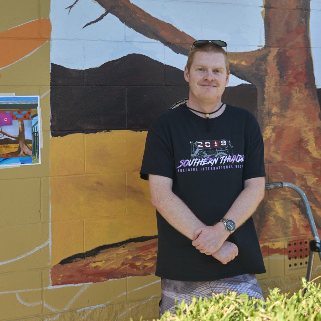 Nathan Smith standing by the work in progress mural.