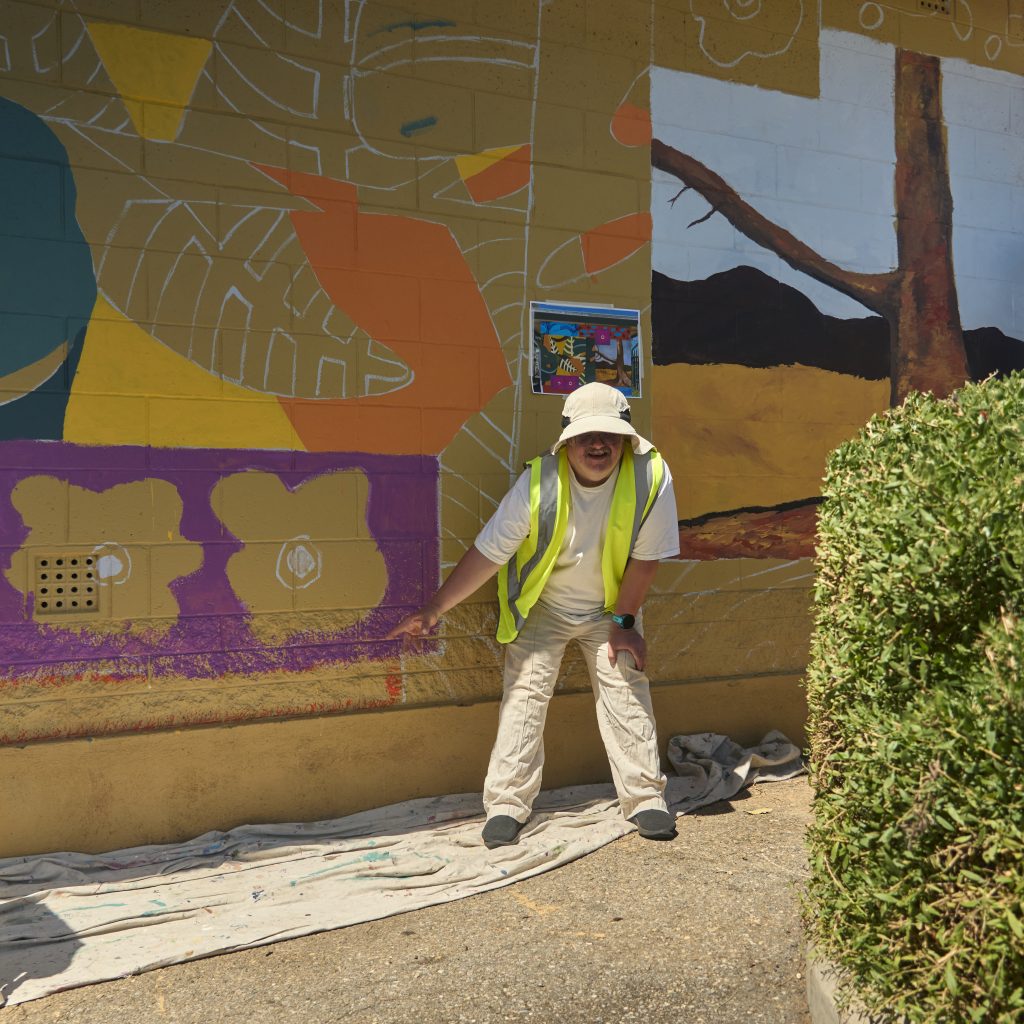 Nathan Dolphin pointing to part of his work on the work in progress mural.